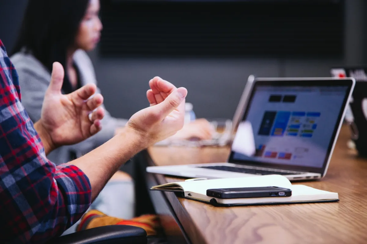 Customer-first culture: a person wearing a red-blue checked shirt is sitting on a chair infront of the laptop