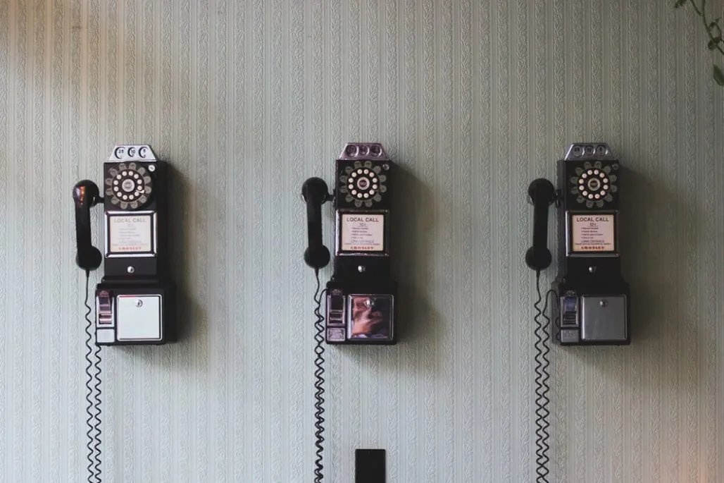 Effective communication - three rotary-dial payphones mounted on a wall next to each other