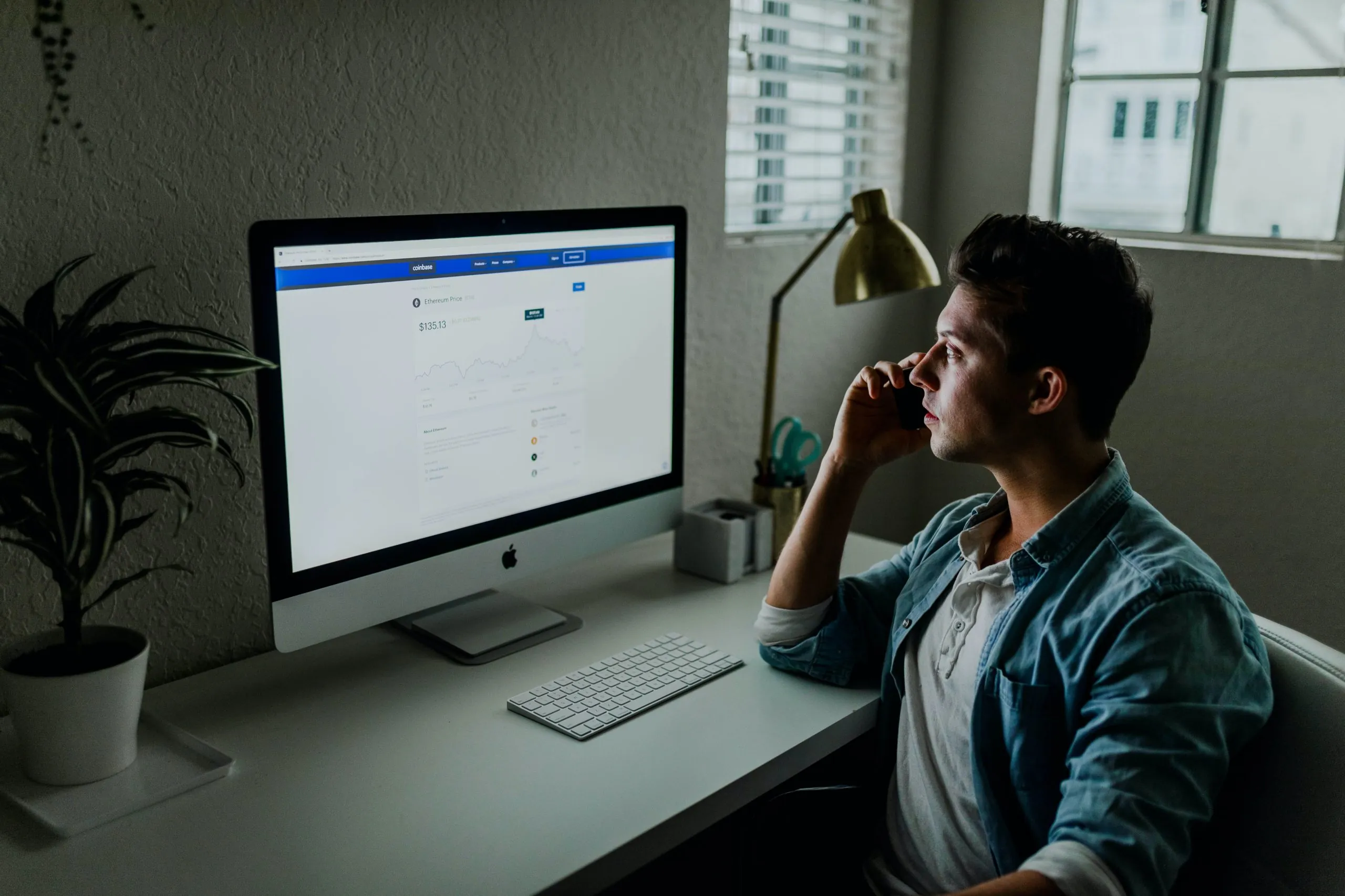 Remote Work tools - man speaking on phone and using desktop computer in home office