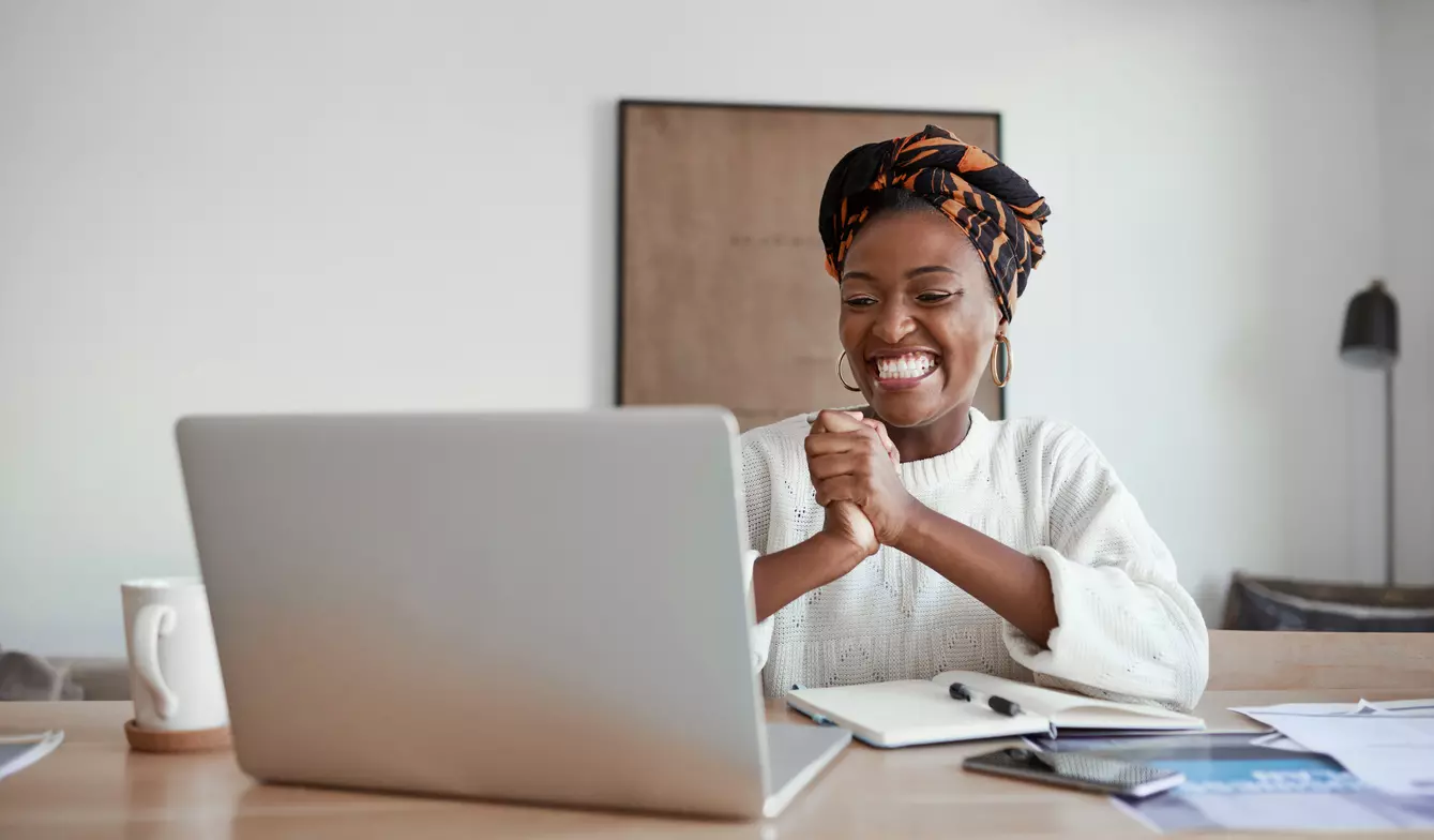 Employee newsletter - woman working from home smiling at computer screen