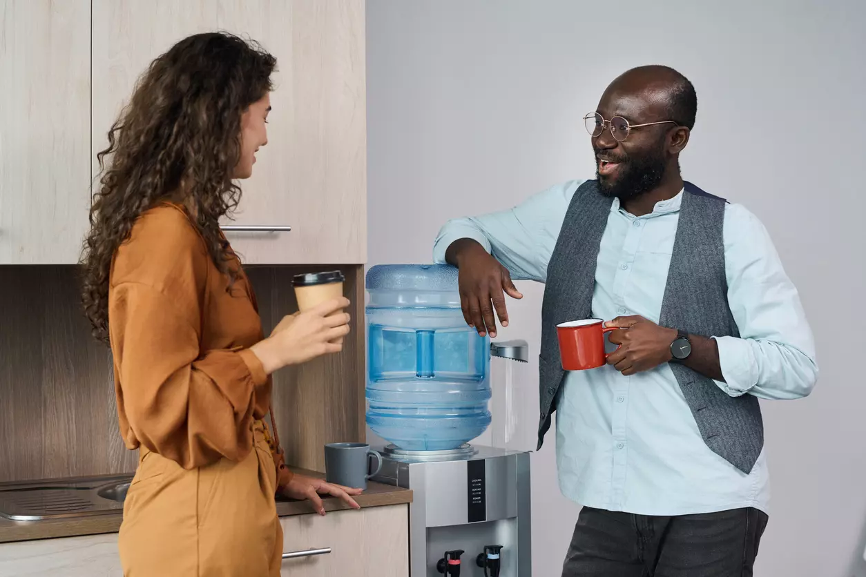 Team building - two colleagues chatting while standing near water cooler