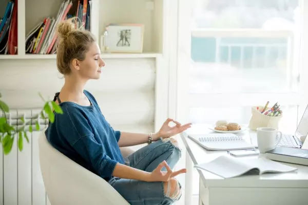 Team building: a woman sitting on a chair in a blue shirt with eyes closed is meditating