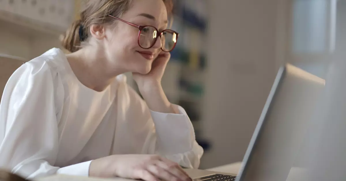 Virtual team bonding - smiling woman with glasses working on laptop