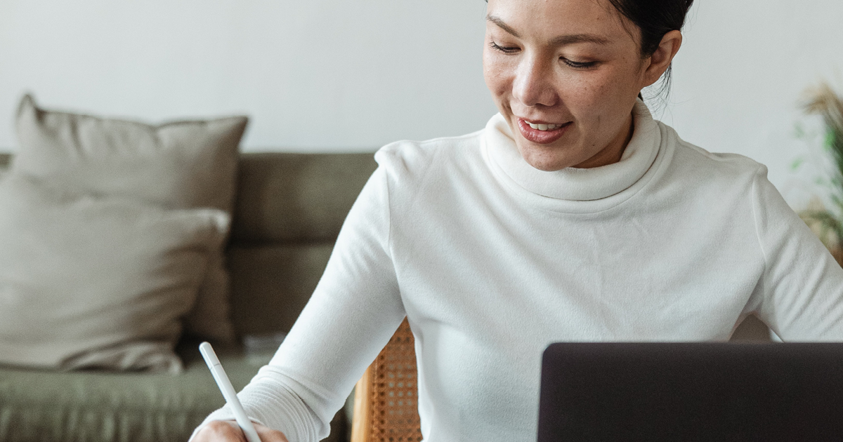 Internal communications manager - female employee in turtleneck sweater working at a laptop