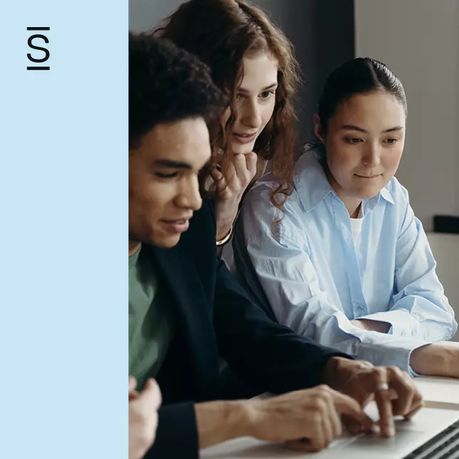 Intranet - male employee works on laptop while two female employees observe