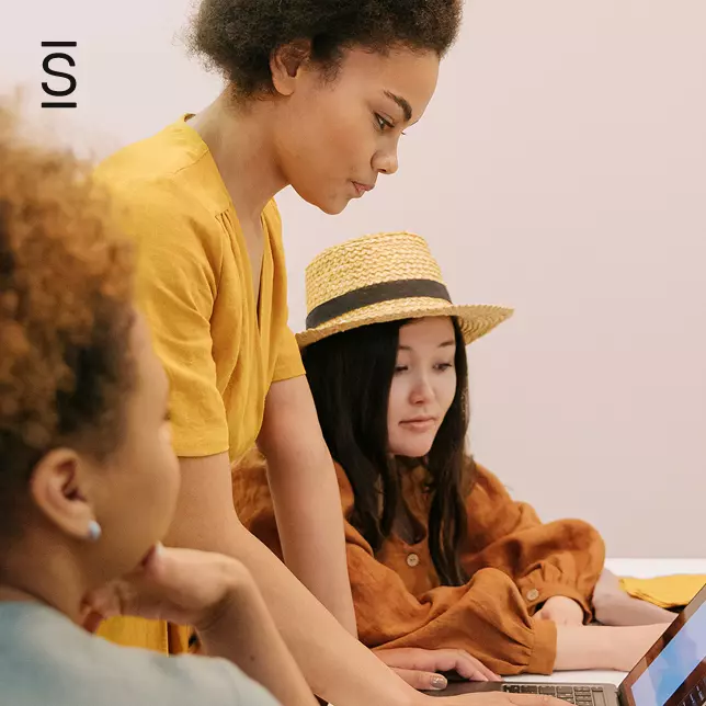 Internal communications technology - three female employees in a meeting looking at a laptop