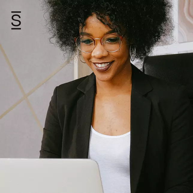 Digital workplace strategy - woman with glasses wearing black blazer using a laptop