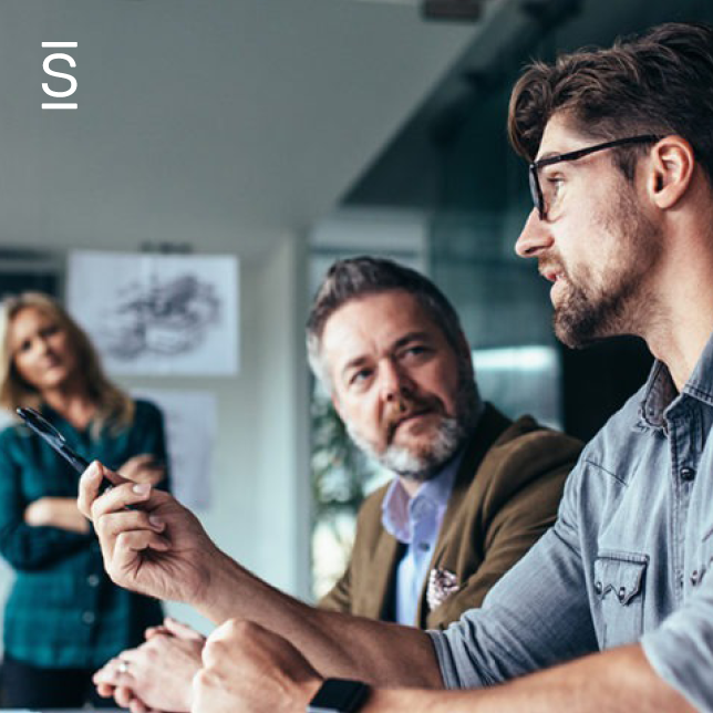 Employee engagement strategy - two male employees speaking while woman in blazer stands in background and listens