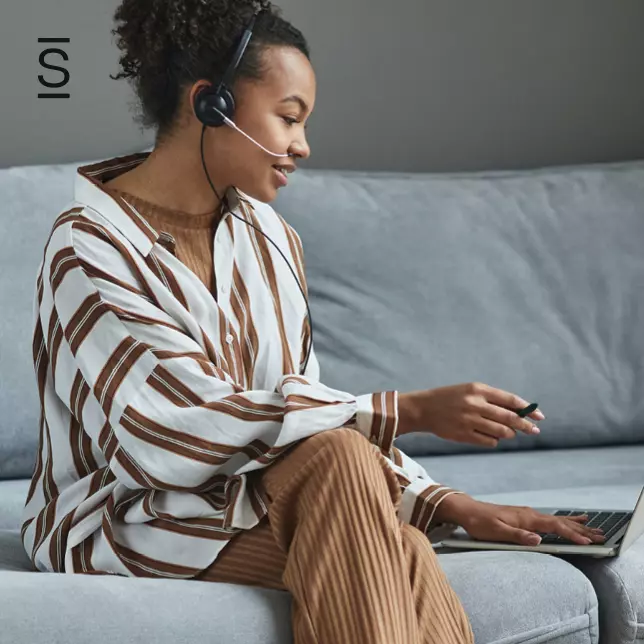 Customer service - woman speaking into headset and looking at laptop screen