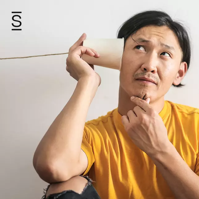 Employee engagement - man in yellow shirt holding cup to his ear