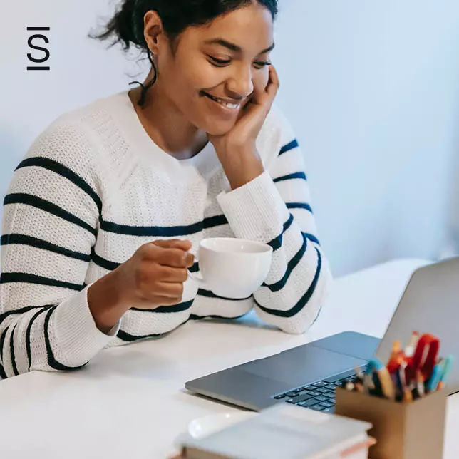 Intranet content - woman holding coffee mug and looking at laptop screen