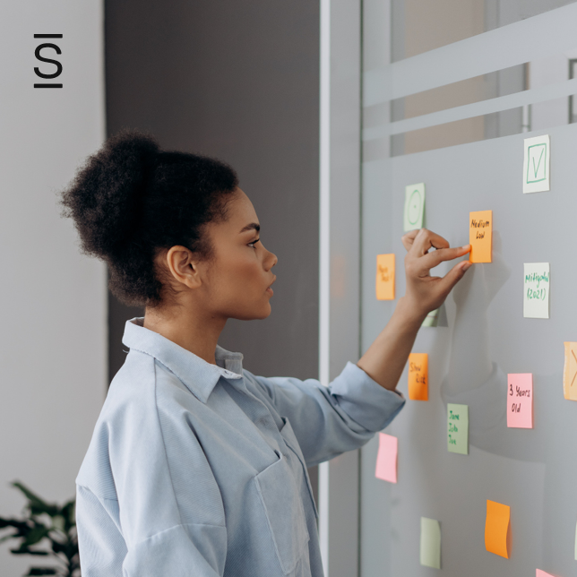 Intranet governance - woman in blue shirt looking at wall with Post-It Notes