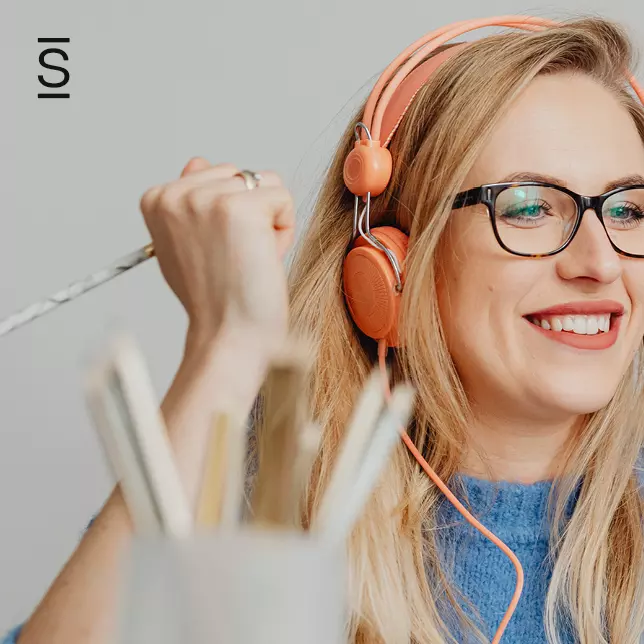 Essential content - woman with glasses and headphones looking at unseen screen