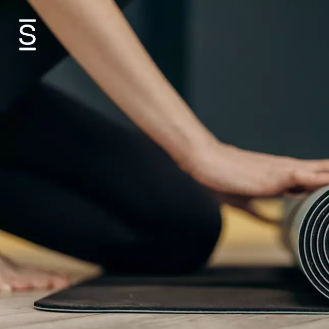 Employee health and well-being - person unrolling a yoga mat