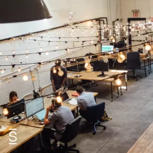 Simpplr Research - wideshot of a shared workspace with multiple employees working on computers