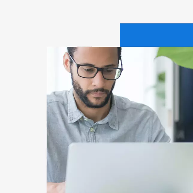 Employee experience - man with glasses in grey polo shirt using laptop