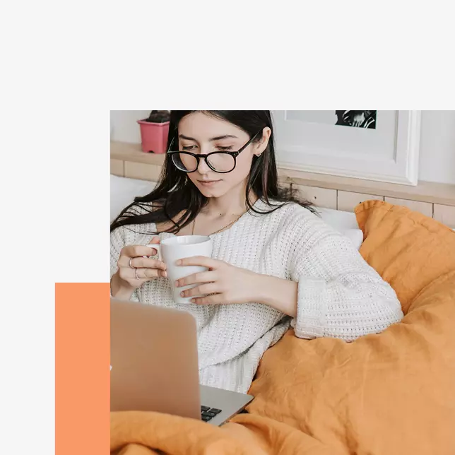 Internal communications - woman with glasses sitting on orange beanbag chair and using Apple laptop