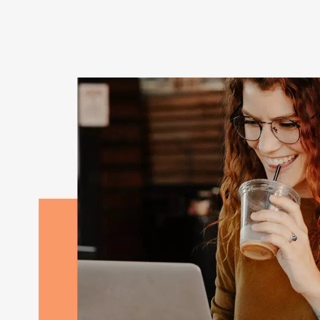 Communications strategy - woman with glasses drinking with straw and looking at computer screen