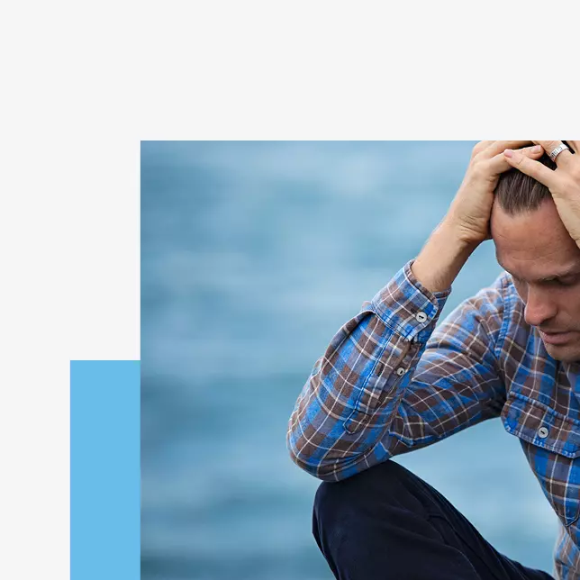 Disengaged workers - male employee in checkered shirt putting hands on head and looking tired and worn out