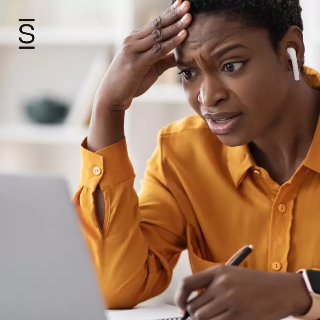 Lack of communication - woman in orange shirt looking at computer screen with confused look on her face