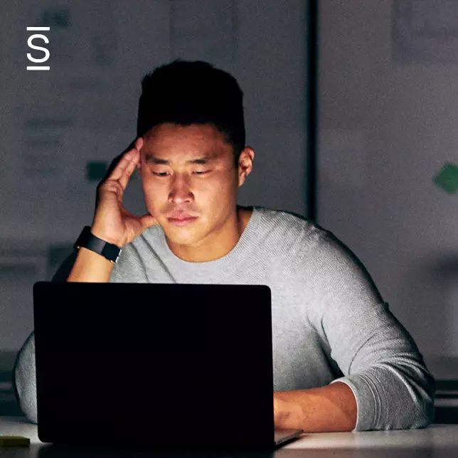 Technology overload - man using laptop computer while looking tired