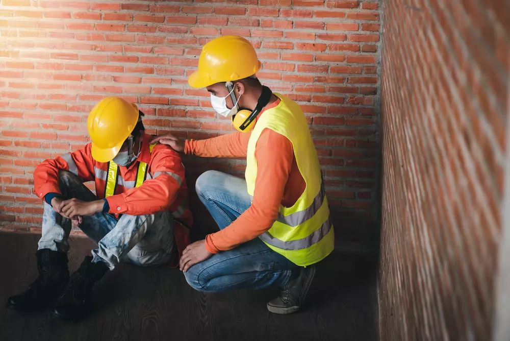 Two construction workers comforting each other