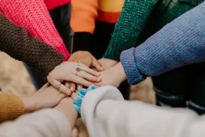 Communication barriers - group of people placing their hands on top of one another to demonstrate teamwork