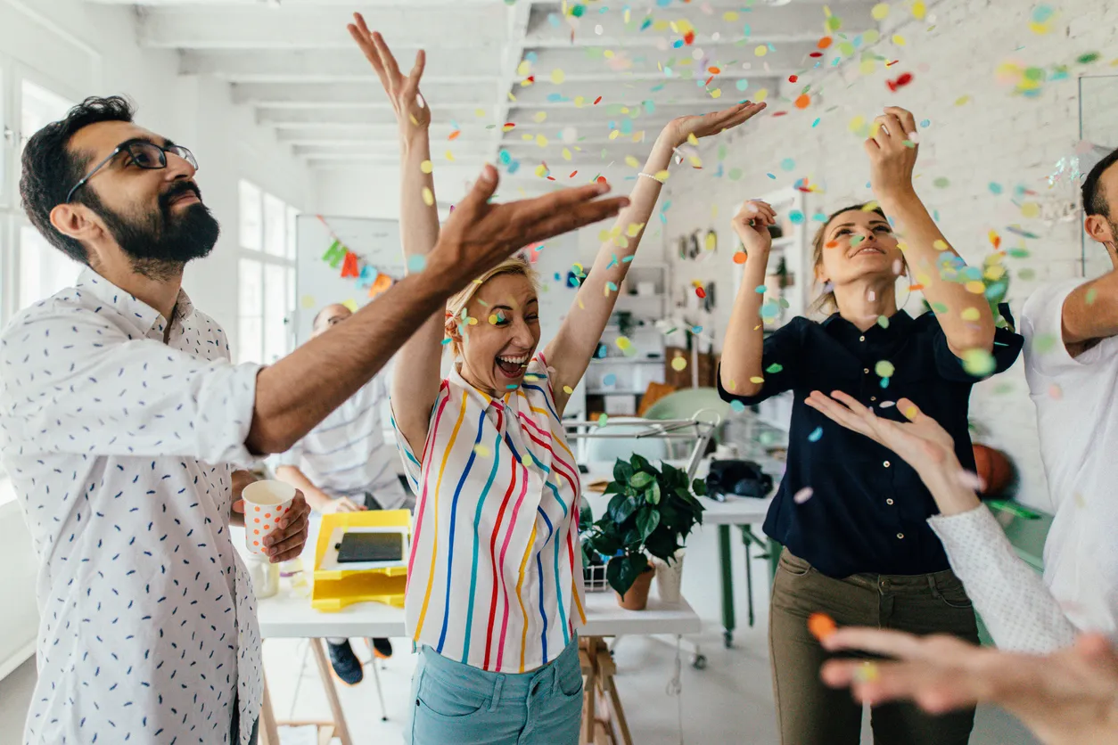 Photo of a group of coworkers having a happy occasion and celebrating together in their office