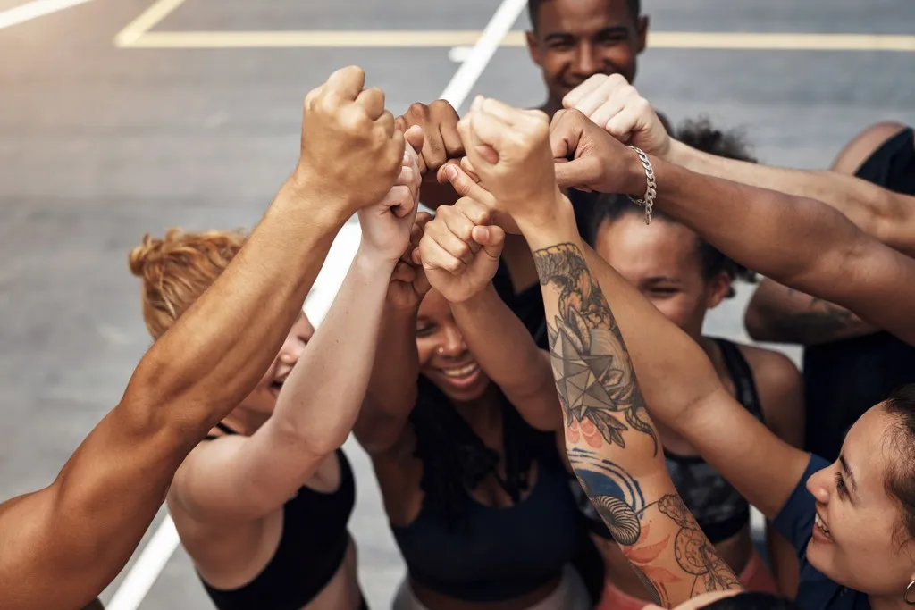 Employee experience - a group of employees raising hands up to demonstrate the power of teamwork