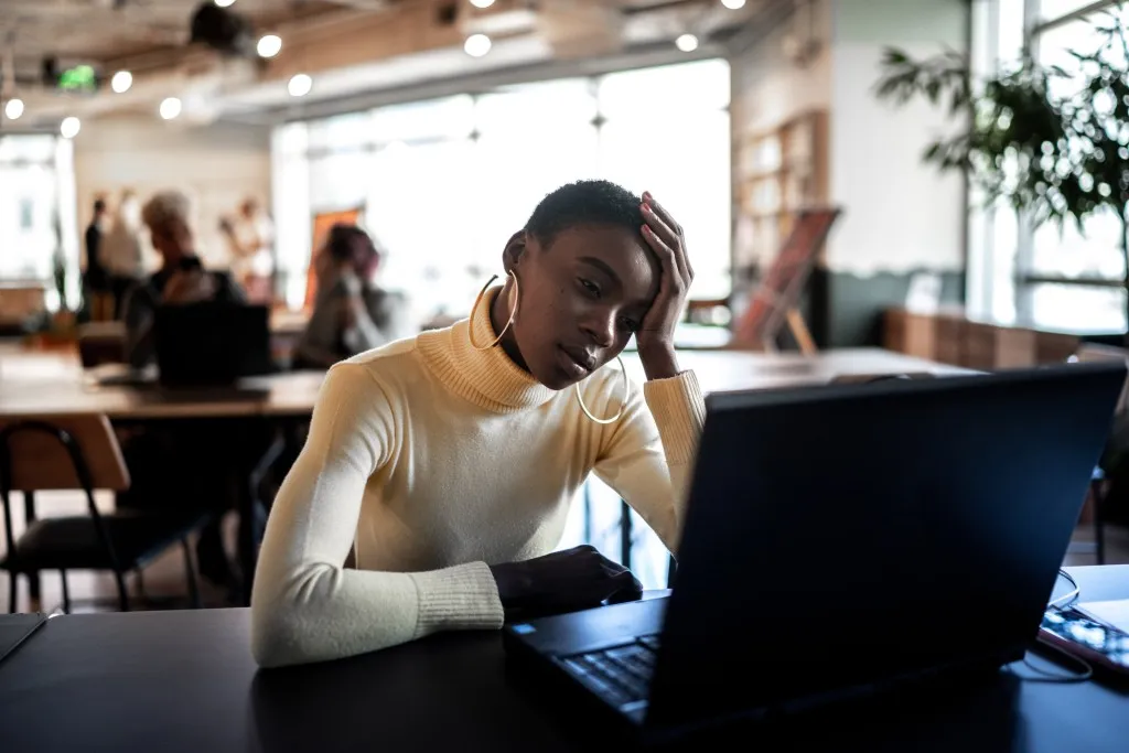 Disengaged employee looking at laptop screen with worried look on her face