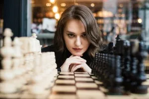 Strategic thinking - a woman playing chess to demonstrate navigating the emotional and behavioral components of employee engagement