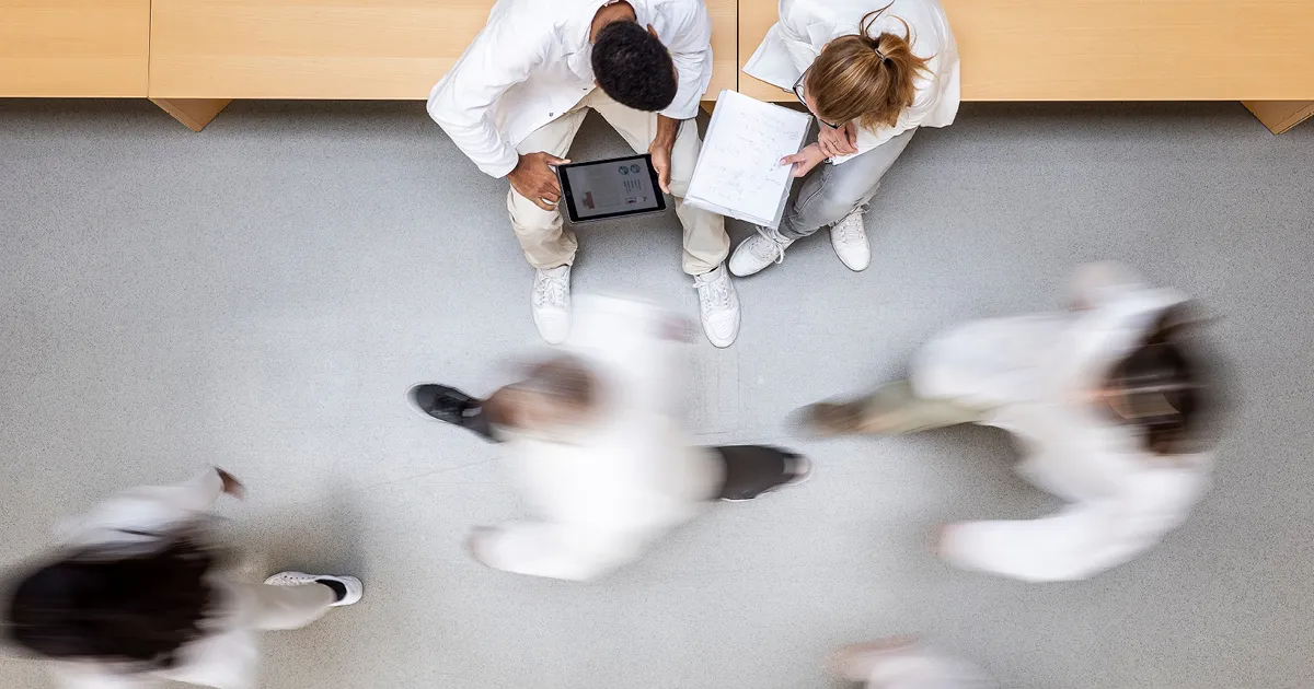 Empowering leaders - male and female doctors looking at a tablet screen in a busy hallway