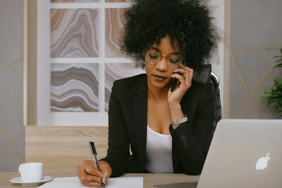 Good leadership - woman in black blazer using smartphone and laptop computer