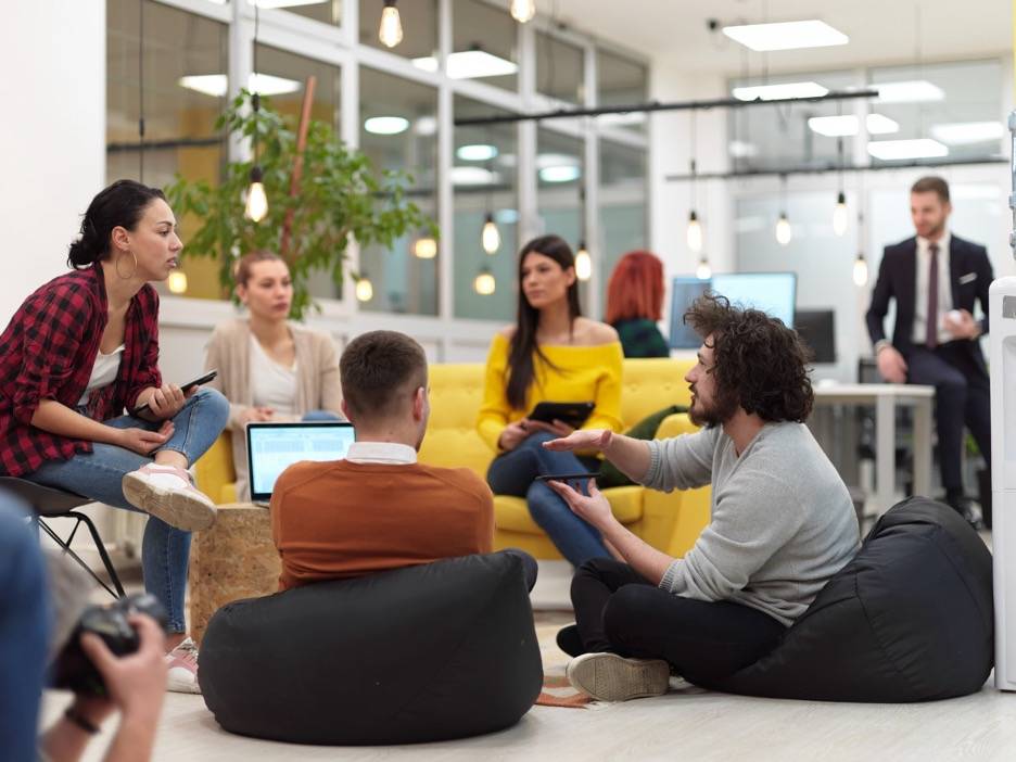 Workplace experience - group of employees sitting in a circle and working in open office space